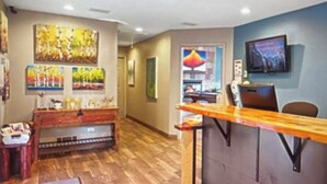 Una hall d'albergo con reception, pavimento in legno e televisore a parete.
