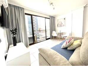 Ein modernes Hotelzimmer mit Balkon, einer Sitzecke, einem kleinen Tisch und einem Fernseher.
