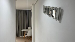 En modern inredning med en matplats som har ett runt bord och stolar, en grå gardin och en metallskulptur som hänger på väggen.