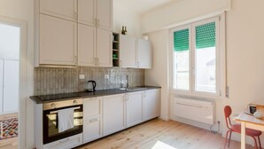A modern kitchen with white cabinets, a black countertop, and a window with green blinds. - GuestHost - Cozy 47 sqm apartment, with modern furniture, located on the third floor of a building with lift (NOT suitable for disabled people - some steps to access), able to comfortably accommodate up to 3 people. The property constitutes the ideal sta (Florence)