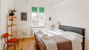 A bedroom with a bed, a chair, a shelf, a window, and a radiator. - GuestHost - Cozy 47 sqm apartment, with modern furniture, located on the third floor of a building with lift (NOT suitable for disabled people - some steps to access), able to comfortably accommodate up to 3 people. The property constitutes the ideal sta (Florence)