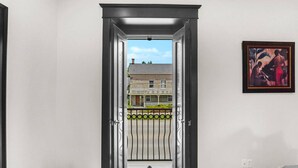 Un couloir avec une porte donnant sur un balcon d’où l’on peut admirer un immeuble d’habitation.