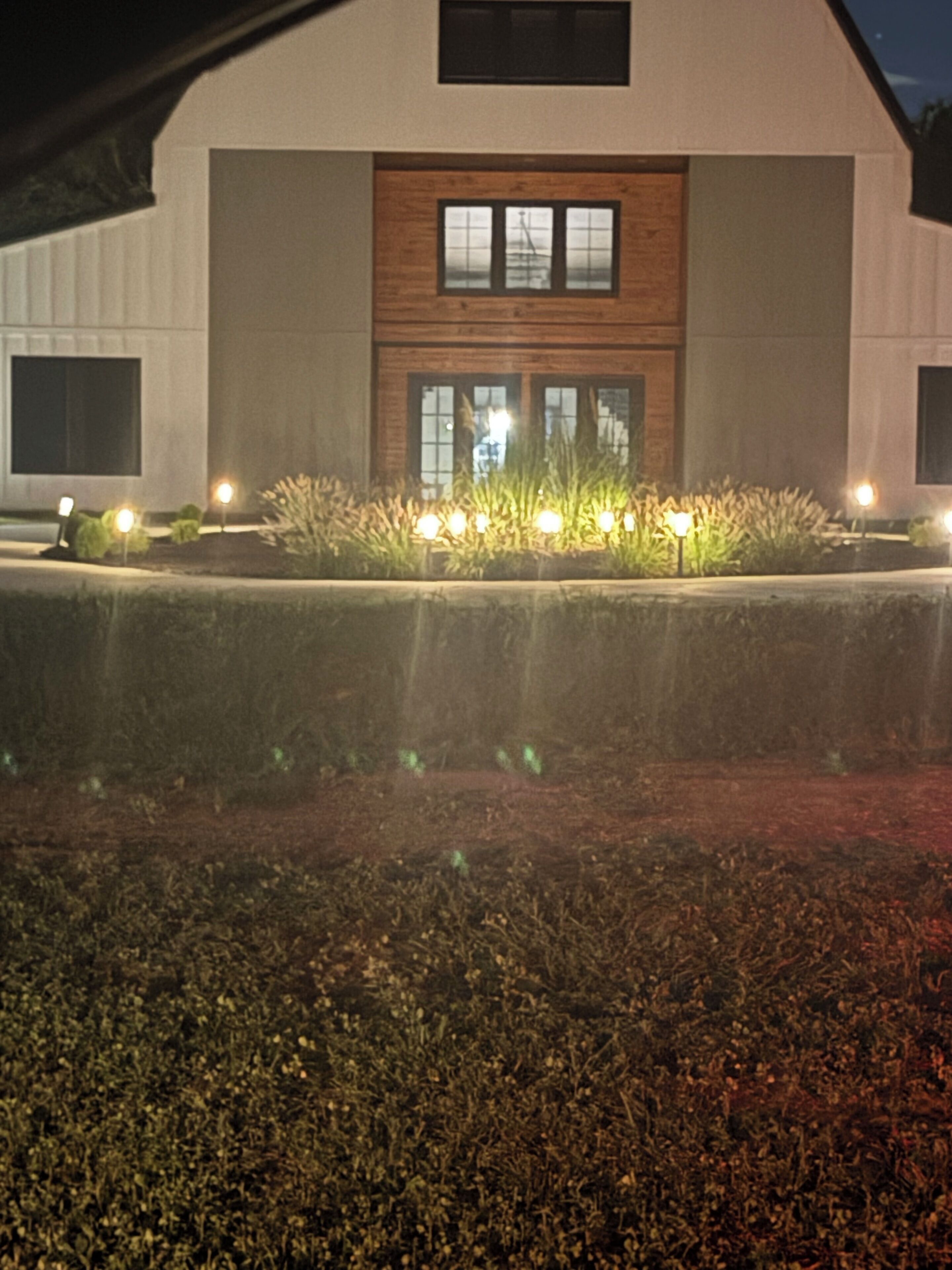 Een modern gebouw met een plat dak, grote ramen en een goed verlichte entree met een tuin.