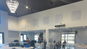 Un salón amplio con mesas y sillas, un árbol de Navidad y una gran lámpara de araña.