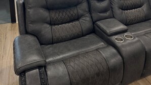 Un sofá seccional de cuero marrón oscuro con un patrón acolchado, ubicado en una sala de estar moderna con piso de madera y puerta de cristal que da al exterior.