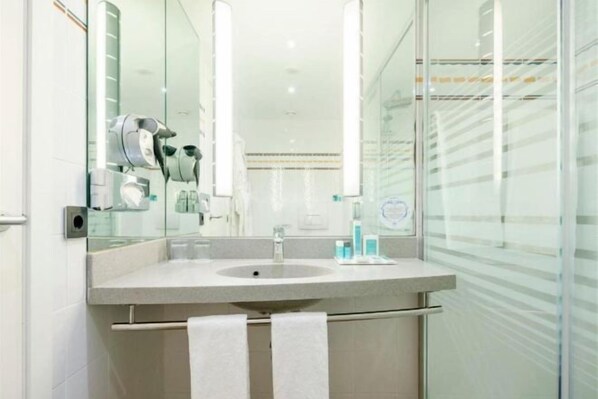 A modern bathroom with a large mirror, a sink, and a towel rack. - Ilunion Valencia 4 (Valencia)
