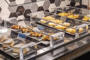 Una vitrina de pastelería con diversos pasteles y postres en recipientes transparentes.