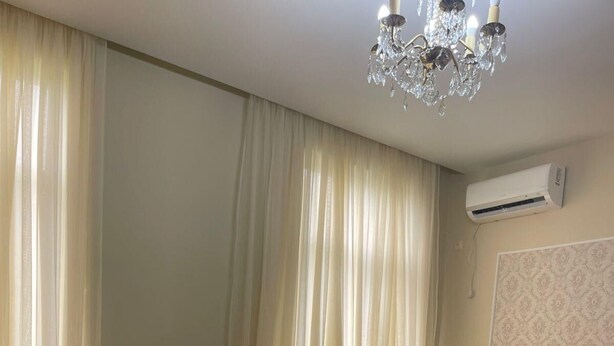 A bedroom with a bed, a chandelier, an air conditioner, and a patterned rug. - Tranquil bed & breakfast with AC in Zugdidi (Zugdidi)