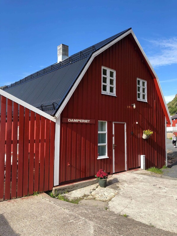 A red building with a sloped roof, a white door, and a window.