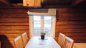 Una mesa de madera con cuatro sillas, una planta en maceta y una ventana que ofrece vistas a edificios.