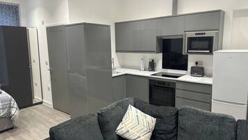 Una cocina moderna con gabinetes grises, microondas, horno y refrigerador.