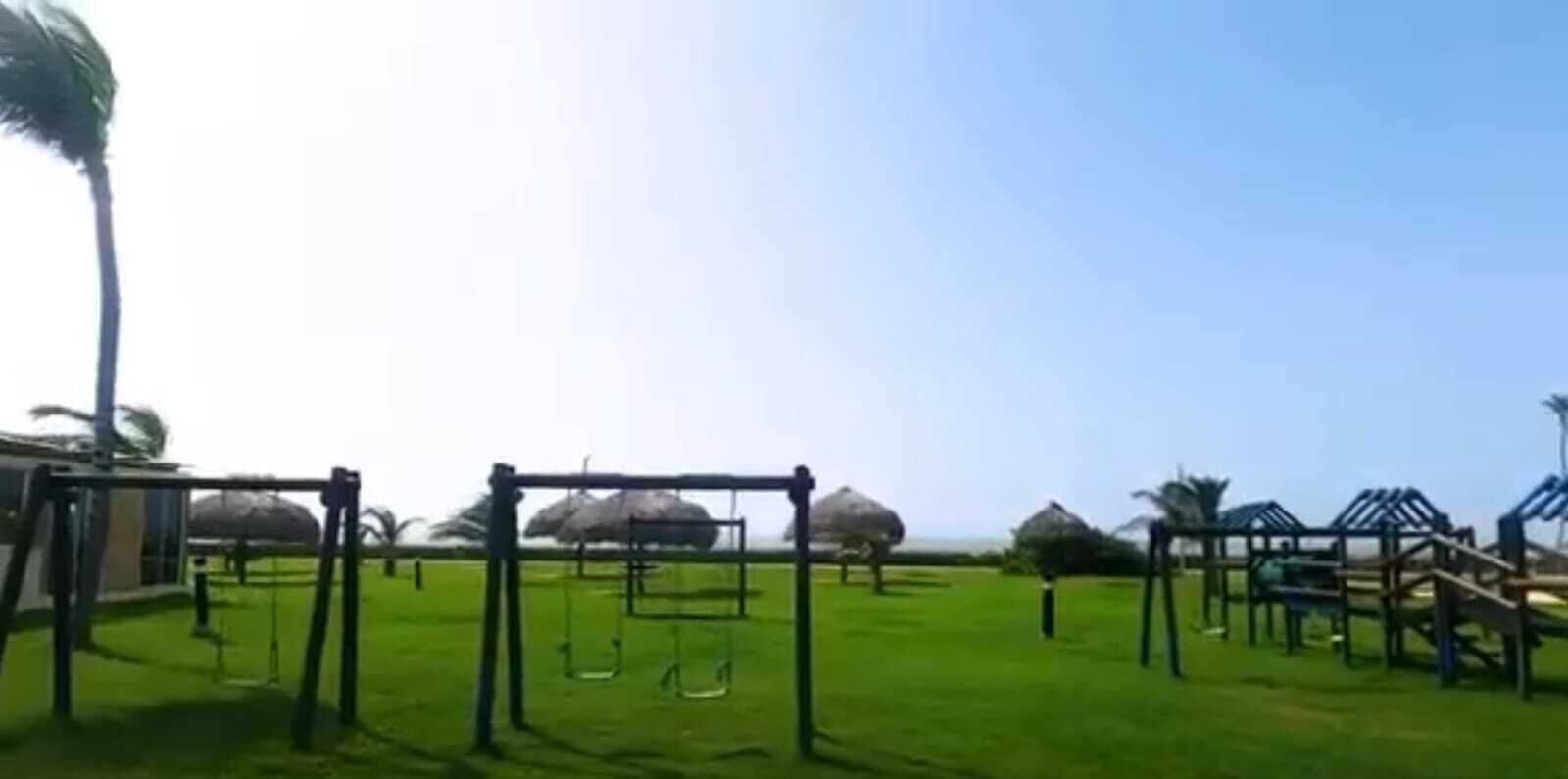 A playground with swings and climbing structures on a grassy field.