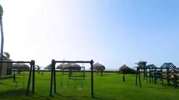 A playground with swings and climbing structures on a grassy field.