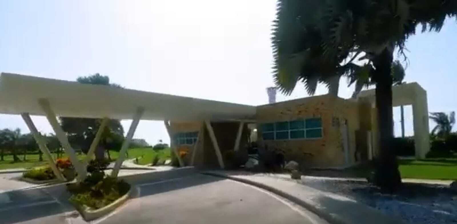 A modern building with a unique architectural design, featuring a curved entrance and a covered area with palm trees.