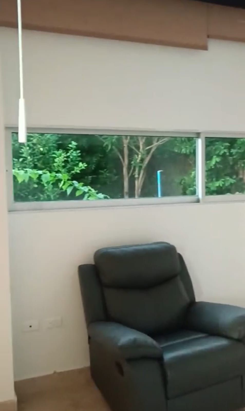 A room with a window, a chair, and a hanging light fixture.