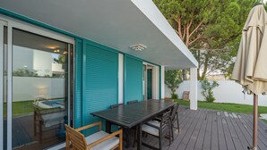 Un patio con mesa y sillas, una puerta corrediza de vidrio y una zona exterior techada.