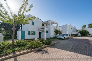A modern building with a white exterior, a paved driveway, and a parked car.