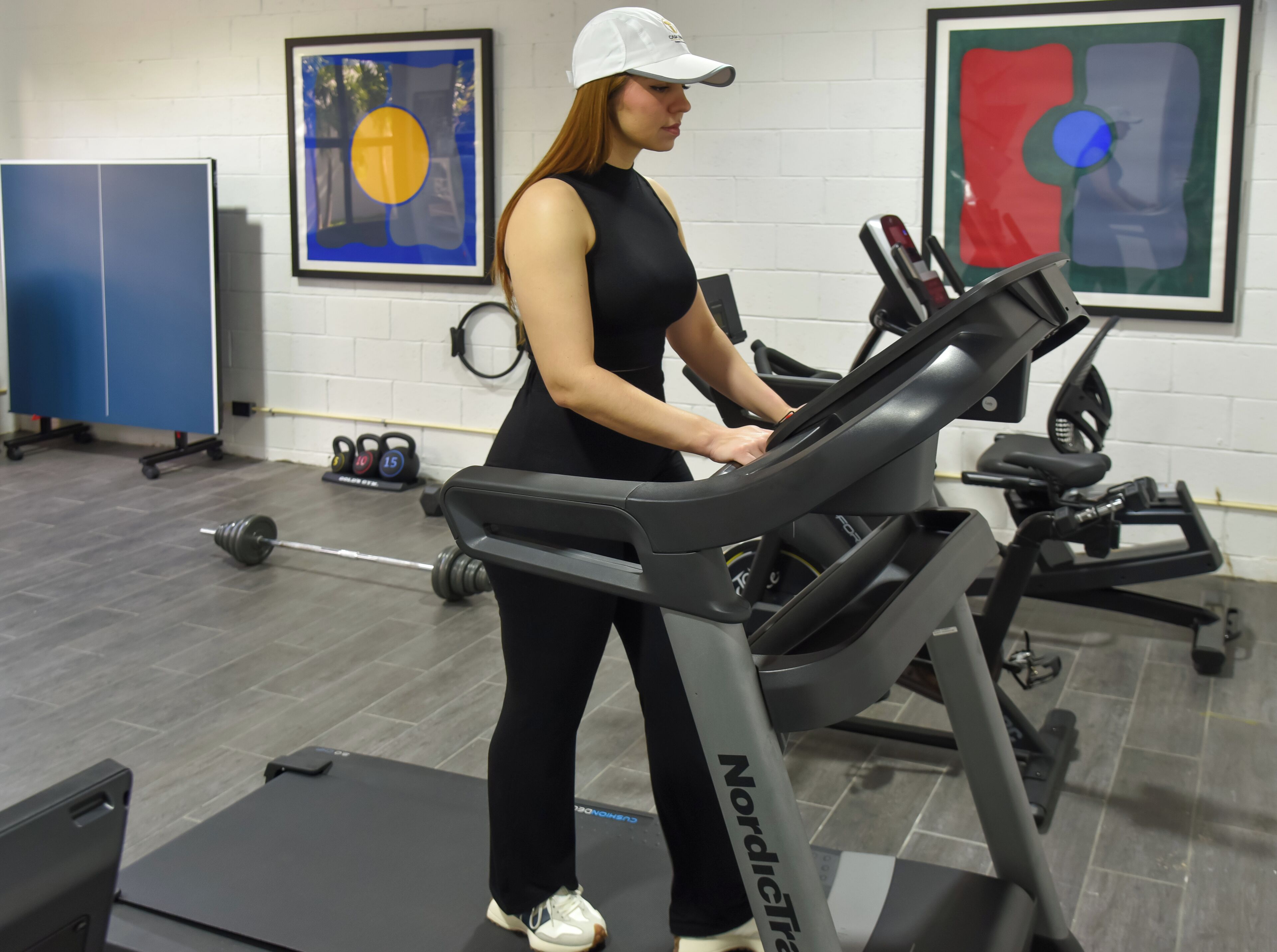 A gym with exercise equipment, a treadmill, weights, and a blue cabinet.