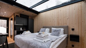 Ein modernes Schlafzimmer mit einem großen Bett, einem Schreibtisch und Blick durch ein Dachfenster.