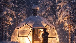 Eine schneebedeckte Kuppelstruktur mit Glastür, eine Person steht davor, und eine Laterne liegt im Schnee.