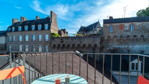 A terrace with a table and chairs, overlooking a historic stone wall and buildings.