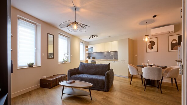 Ein modernes Wohnzimmer mit Sofa, Couchtisch und Essbereich mit Stühlen.