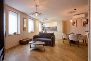 Un salon moderne comprenant un canapé, une table basse et un coin repas avec des chaises.