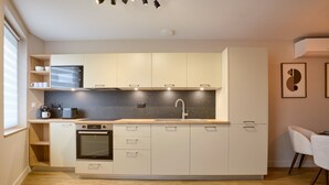 Eine moderne Küche mit Einbauofen, Mikrowelle und Spüle. Holzregale und eine weiße Arbeitsplatte sind vorhanden.
