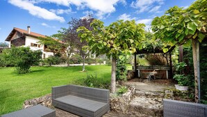 Een terras met rieten meubilair, een stenen muur en een pergola met klimplanten.