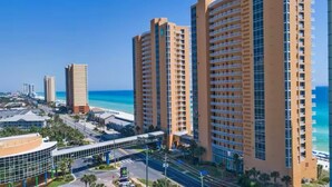 Ein Hochhaus-Hotel mit mehreren Etagen, Blick auf den Strand und ein modernes Gebäude mit Glasfassade in der Nähe.