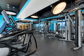 Een fitnessruimte met loopbanden, krachtapparaten en losse gewichten.
