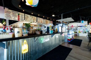 Uma área de bar com letreiro de neon, cardápios e diversos equipamentos.