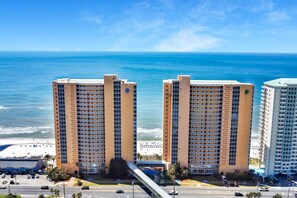 Dois edifícios altos com uma praia e o oceano ao fundo.