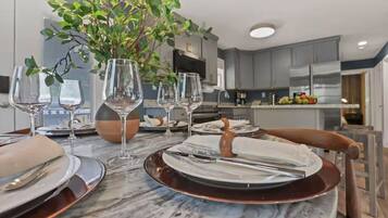 A modern dining area with a marble table, wine glasses, and a potted plant.
