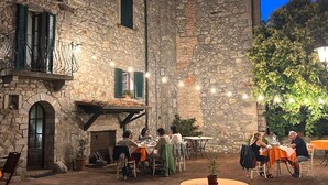 Zona pranzo all'aperto con pareti in pietra, tavoli e sedie.