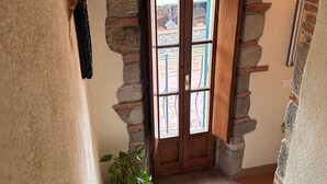Un pasillo con un arco de ladrillo, una puerta de madera y una planta en maceta.