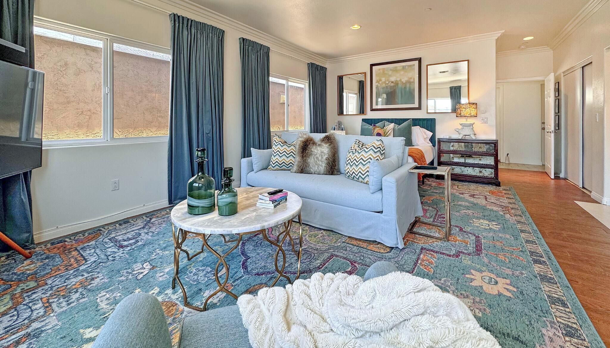 Un salon avec un canapé, une table basse, un téléviseur et un tapis à motifs.