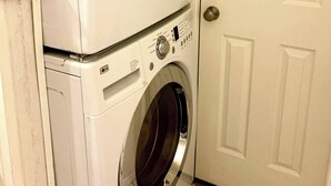 A stacked washer and dryer unit in a room with a white door. - Lovely 2 bedroom condo with patio minutes from LSU (Baton Rouge)