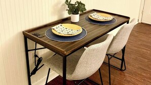 A dining table with two chairs, a potted plant, and a decorative plate on the table. - Lovely 2 bedroom condo with patio minutes from LSU (Baton Rouge)