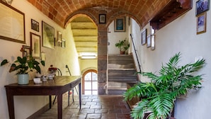 A stone-floored hallway with a wooden table, potted plants, and a staircase leading to an upper level. - Uva Spina – Intimate Double Room with Val di Farma View (Piloni)