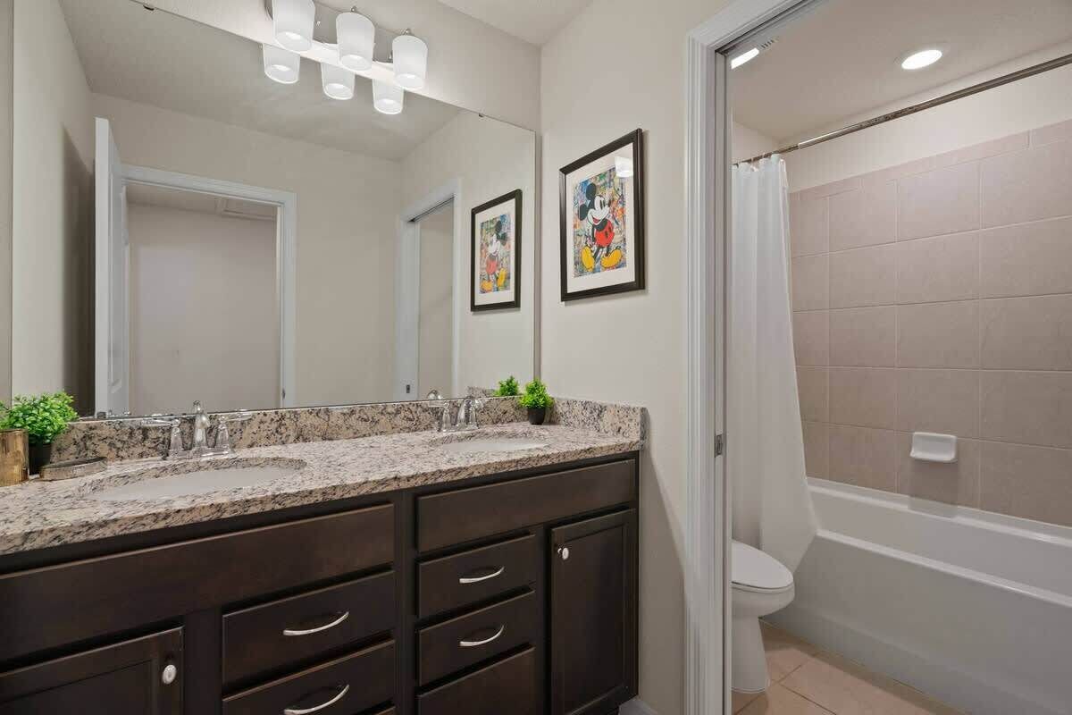 A bathroom with a double sink vanity, a toilet, and a shower area.