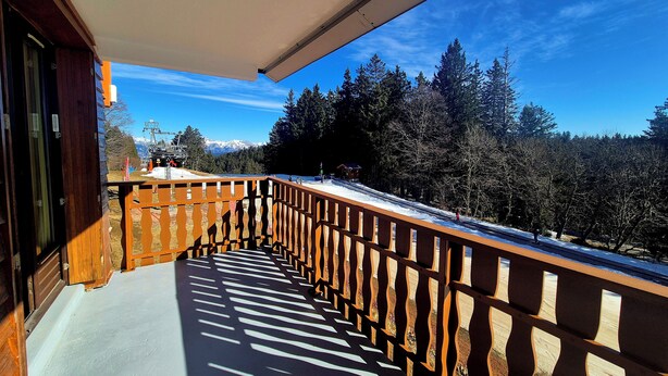 A balcony with a view of a snowy mountain landscape and a ski lift in the background.