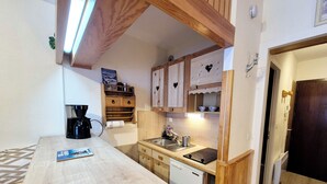 A compact kitchen with wooden cabinets, a coffee maker, and a dishwasher.