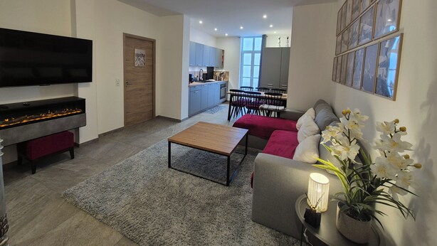 Un salon moderne avec un téléviseur à écran plat, une cheminée, un canapé et un coin repas à l’arrière-plan.