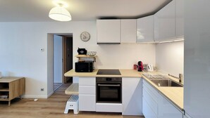 A modern kitchen with white cabinets, a black oven, a microwave, and a wooden countertop.