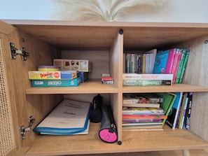 Ein Holzbücherregal mit verschiedenen Gegenständen, darunter Bücher, ein Brettspiel und ein Schlüsselbund.