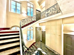 Un escalier orné de rampes en métal décoratives, offrant une vue sur l’intérieur, notamment une porte et des fenêtres.