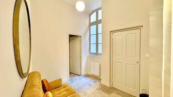 A spacious hallway with a large mirror, a sofa with cushions, a radiator, and a door.