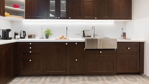 Une cuisine moderne avec des meubles de rangement en bois foncé, un évier en acier inoxydable et un plan de travail blanc.