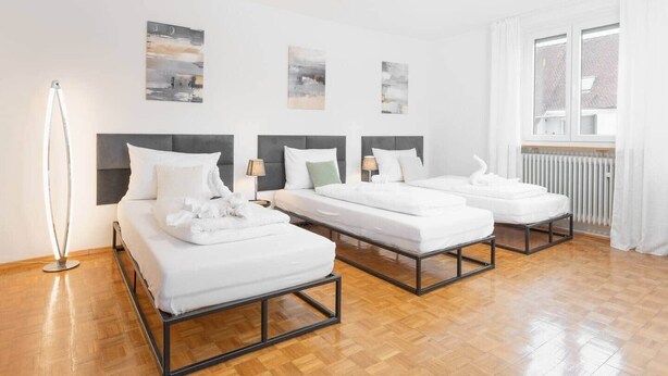 Une chambre d’hôtel avec deux lits, une lampe sur pied et des œuvres d’art accrochées aux murs.